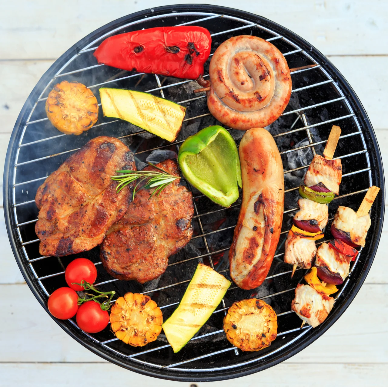 Ein Grill mit unterschiedlichen Fleischsorten, Würsten und Gemüse. - Ein Grill mit unterschiedlichen Fleischsorten, Würsten und Gemüse.
